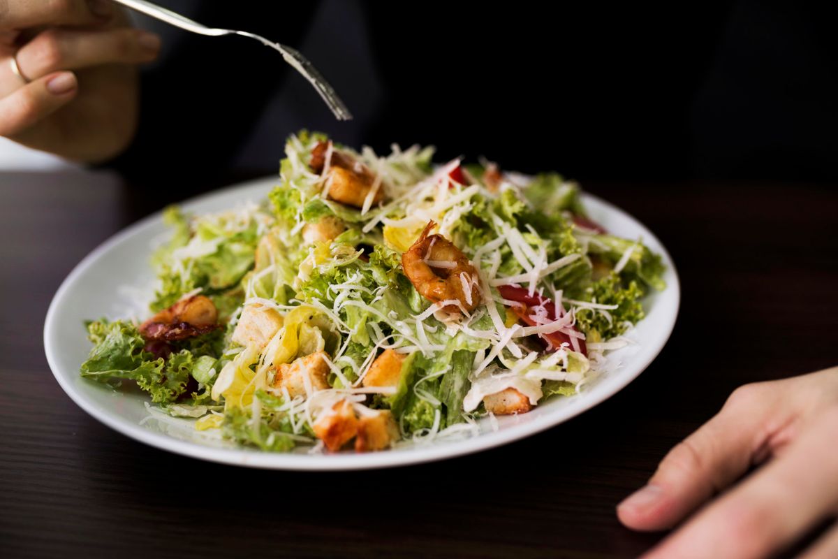 person-eating-tasty-caesar-salad-with-croutons-restaurant